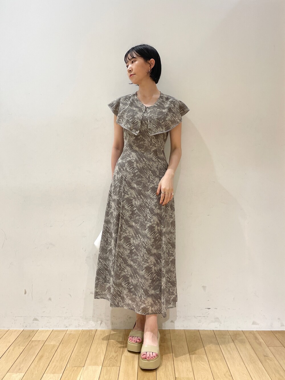 グレー系のワンピース、ホワイト系のハンドバッグ、ベージュ系のサンダルを着用したレディースの夏コーディネートの2枚目の写真