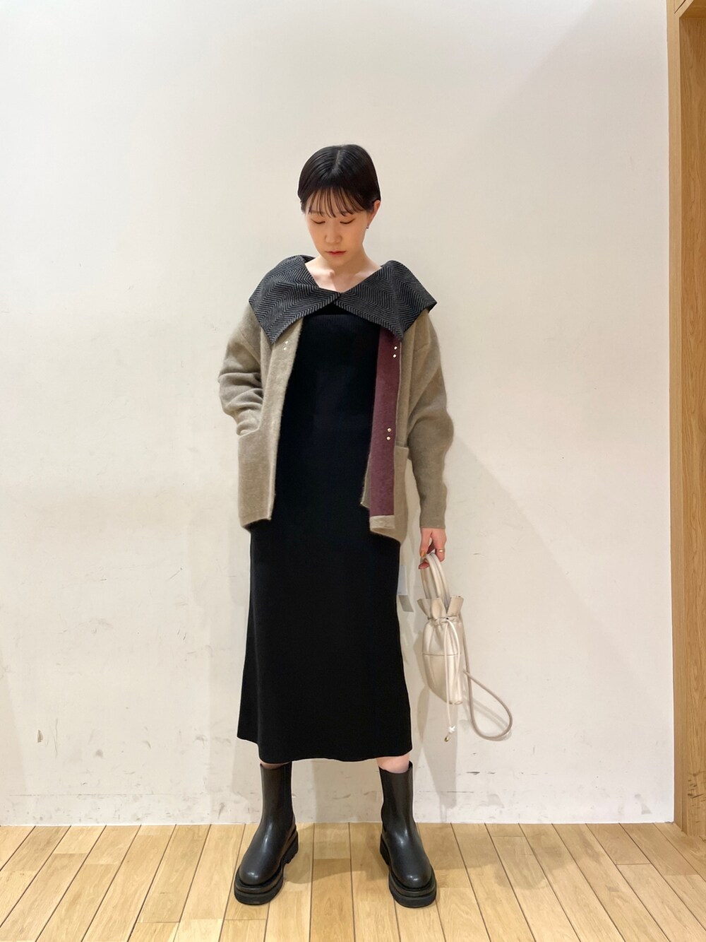 ブラック系のワンピース、ホワイト系のハンドバッグ、ブラック系のブーツを着用したレディースの冬コーディネートの8枚目の写真