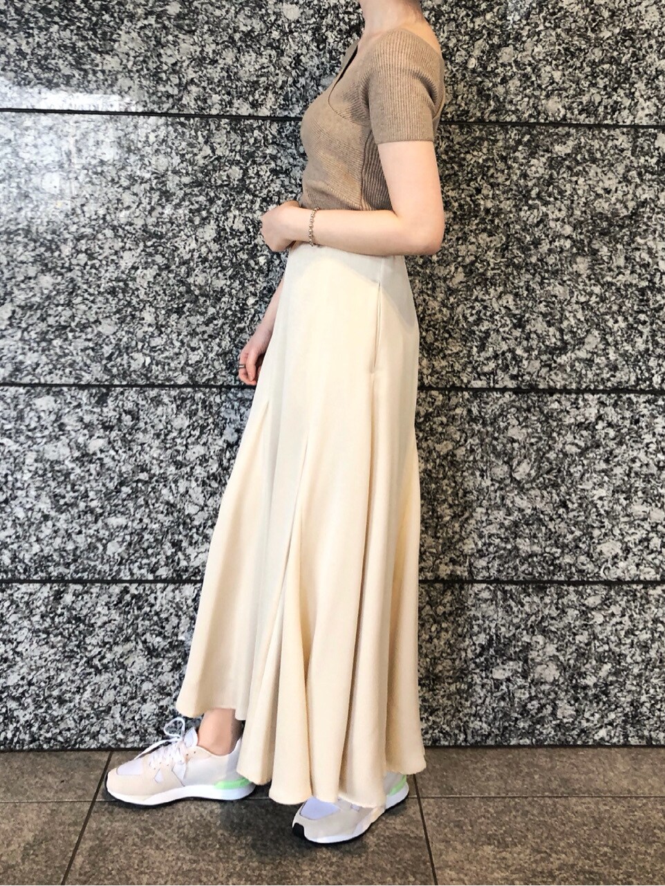 ベージュ系のニット/セーター、ホワイト系のスニーカー、ホワイト系のスカートを着用したレディースの春コーディネートの5枚目の写真