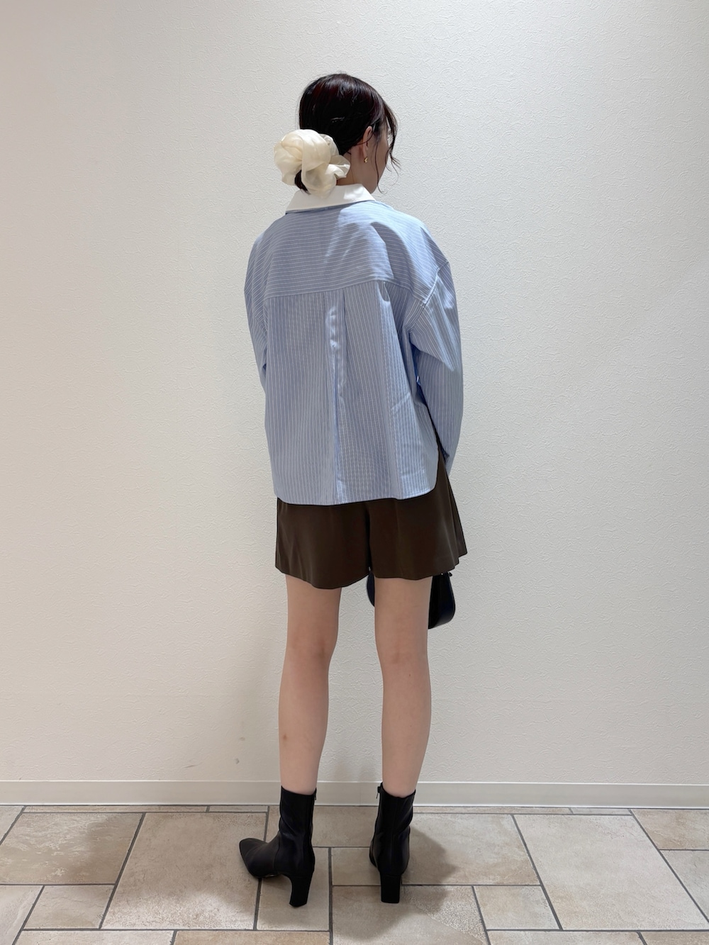 ブルー系のシャツ/ブラウス、ブラック系のハンドバッグ、ブラック系のブーツを着用したレディースの夏コーディネートの4枚目の写真