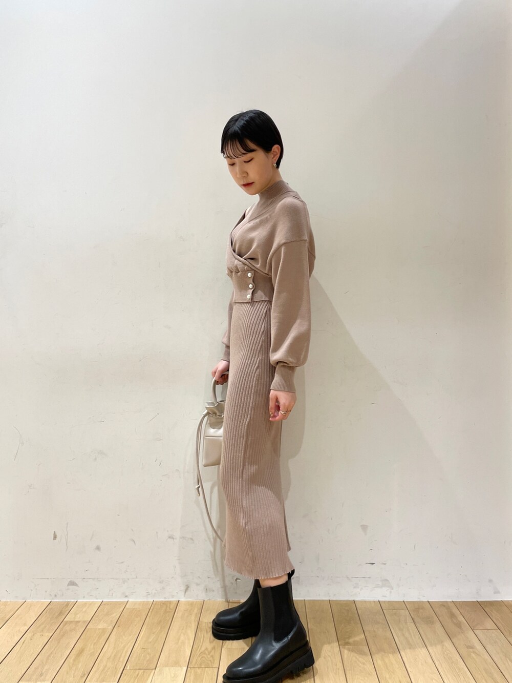 ベージュ系のワンピース、ホワイト系のハンドバッグ、ブラック系のブーツを着用したレディースの冬コーディネートの4枚目の写真