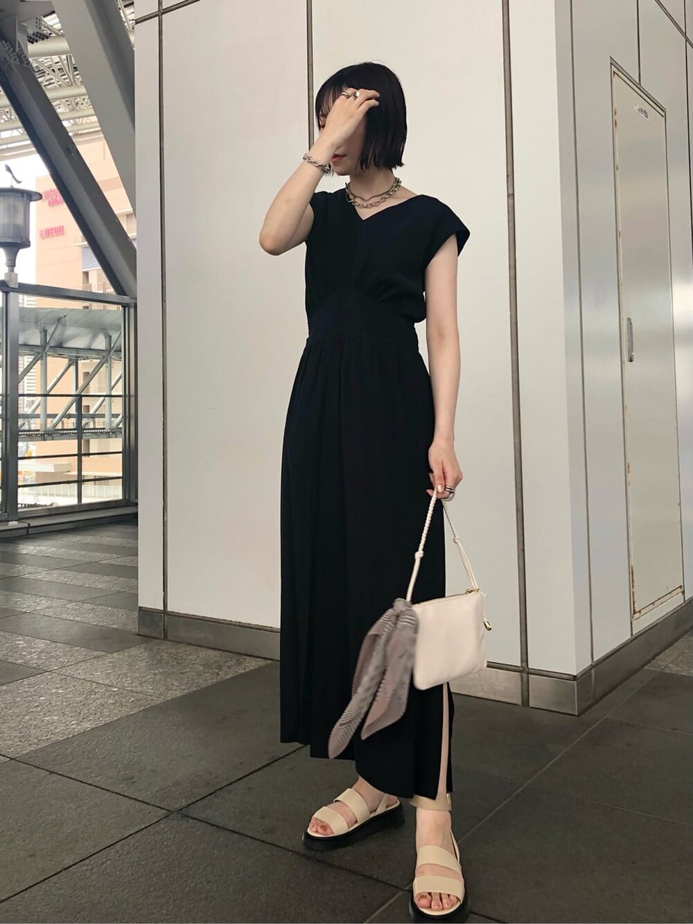 ホワイト系のショルダーバッグ、ブラック系のワンピース、ホワイト系のサンダルを着用したレディースの夏コーディネートの5枚目の写真