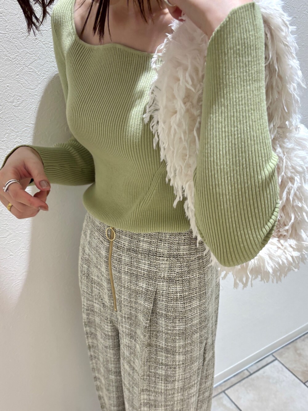 ホワイト系のその他パンツ、グリーン系のニット/セーター、ホワイト系のハンドバッグを着用したレディースの冬コーディネートの6枚目の写真