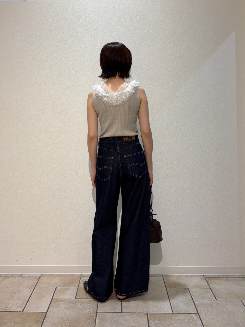 ベージュ系のニット/セーター、ブルー系のデニムパンツ、ブラウン系のサンダルを着用したレディースの夏コーディネートの3枚目の写真