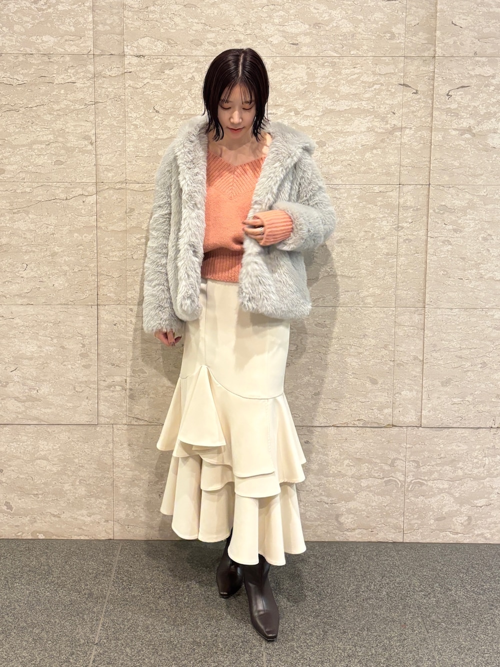 ピンク系のニット/セーター、ブラウン系のブーツ、ホワイト系のスカートを着用したレディースの冬コーディネートの2枚目の写真
