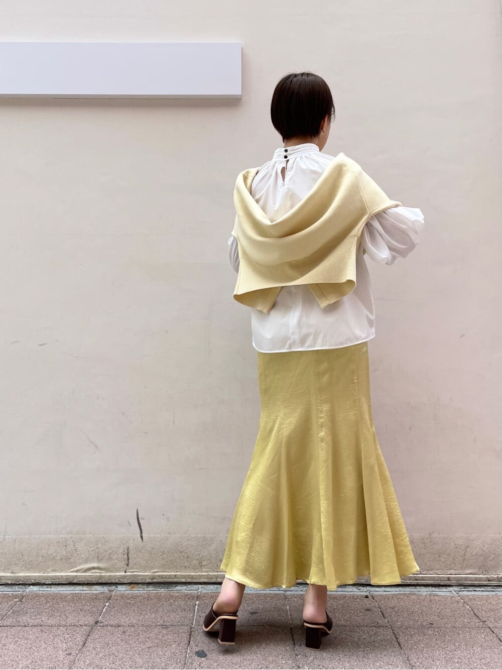 ホワイト系のシャツ/ブラウス、イエロー系のスカート、ベージュ系のハンドバッグを着用したレディースの冬コーディネートの3枚目の写真