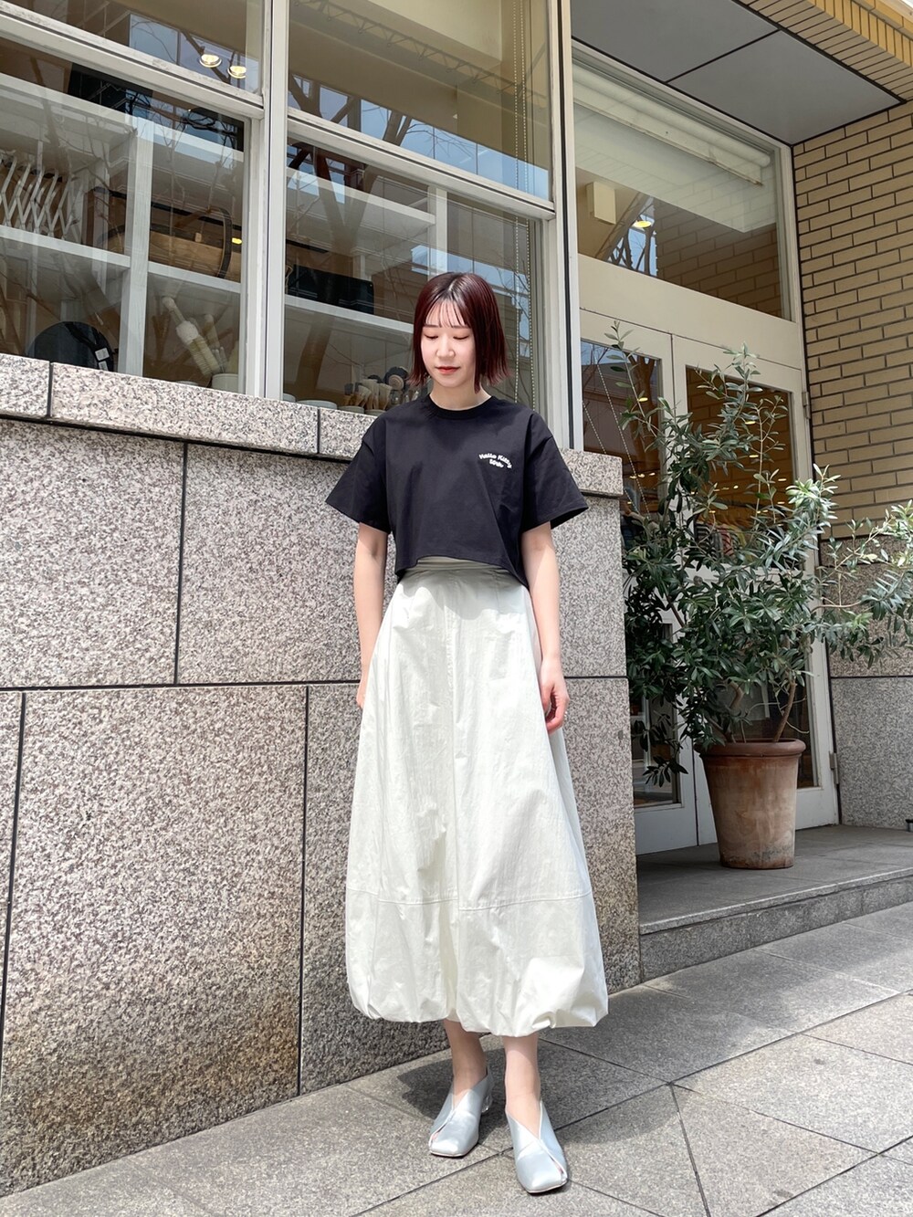シルバー系のパンプス、ブラック系のTシャツ/カットソー、ホワイト系のスカートを着用したレディースの春コーディネートの4枚目の写真