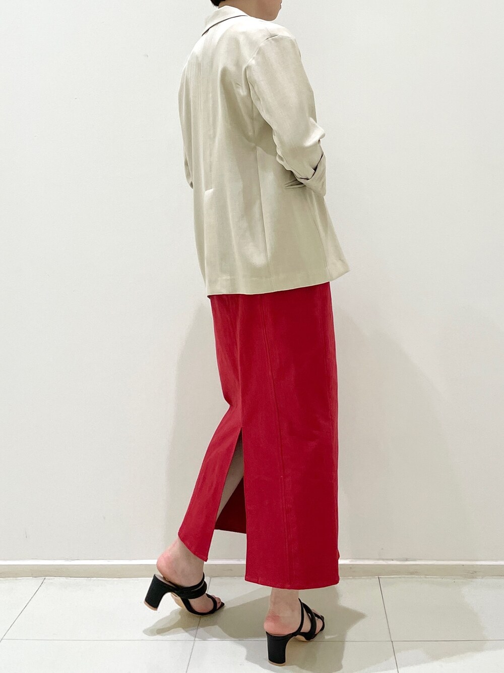 レッド系のスカート、ブラック系のサンダル、ベージュ系のテーラードジャケットを着用したレディースの春コーディネートの6枚目の写真