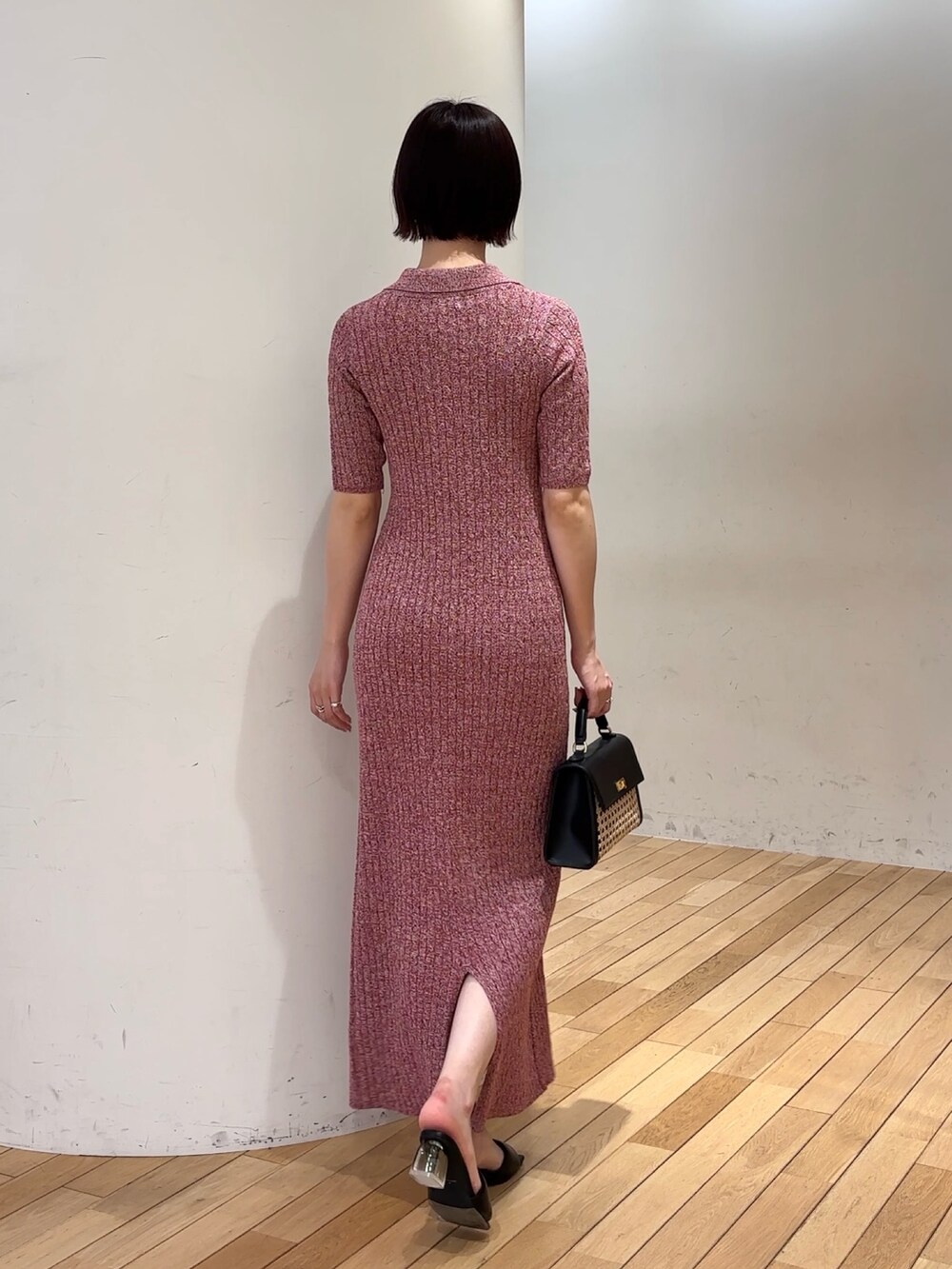レッド系のワンピース、ブラック系のハンドバッグ、ブラック系のサンダルを着用したレディースの春コーディネートの3枚目の写真