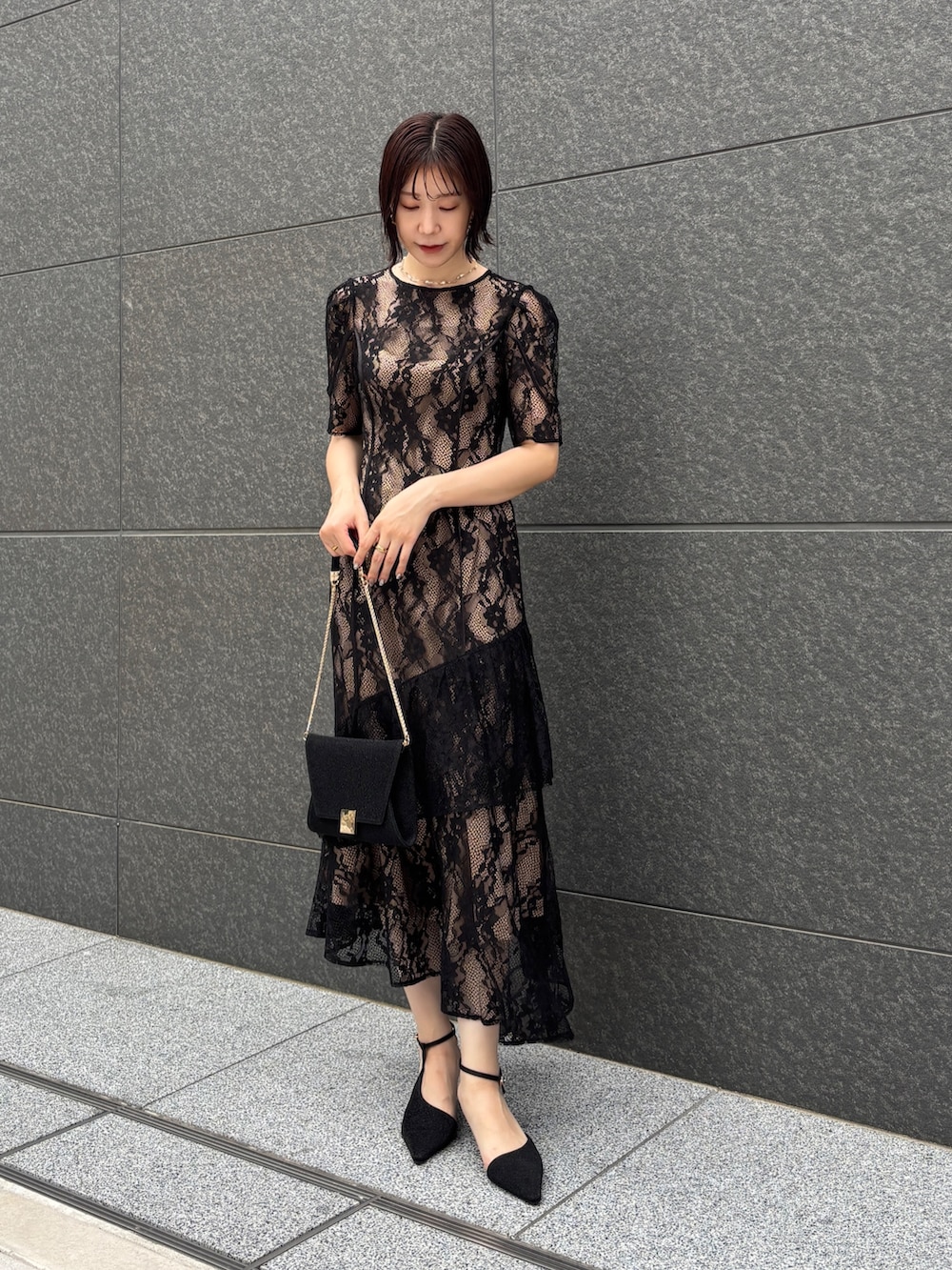 ブラック系のドレス、ブラック系のクラッチバッグ、ブラック系のパンプスを着用したレディースの秋コーディネートの3枚目の写真