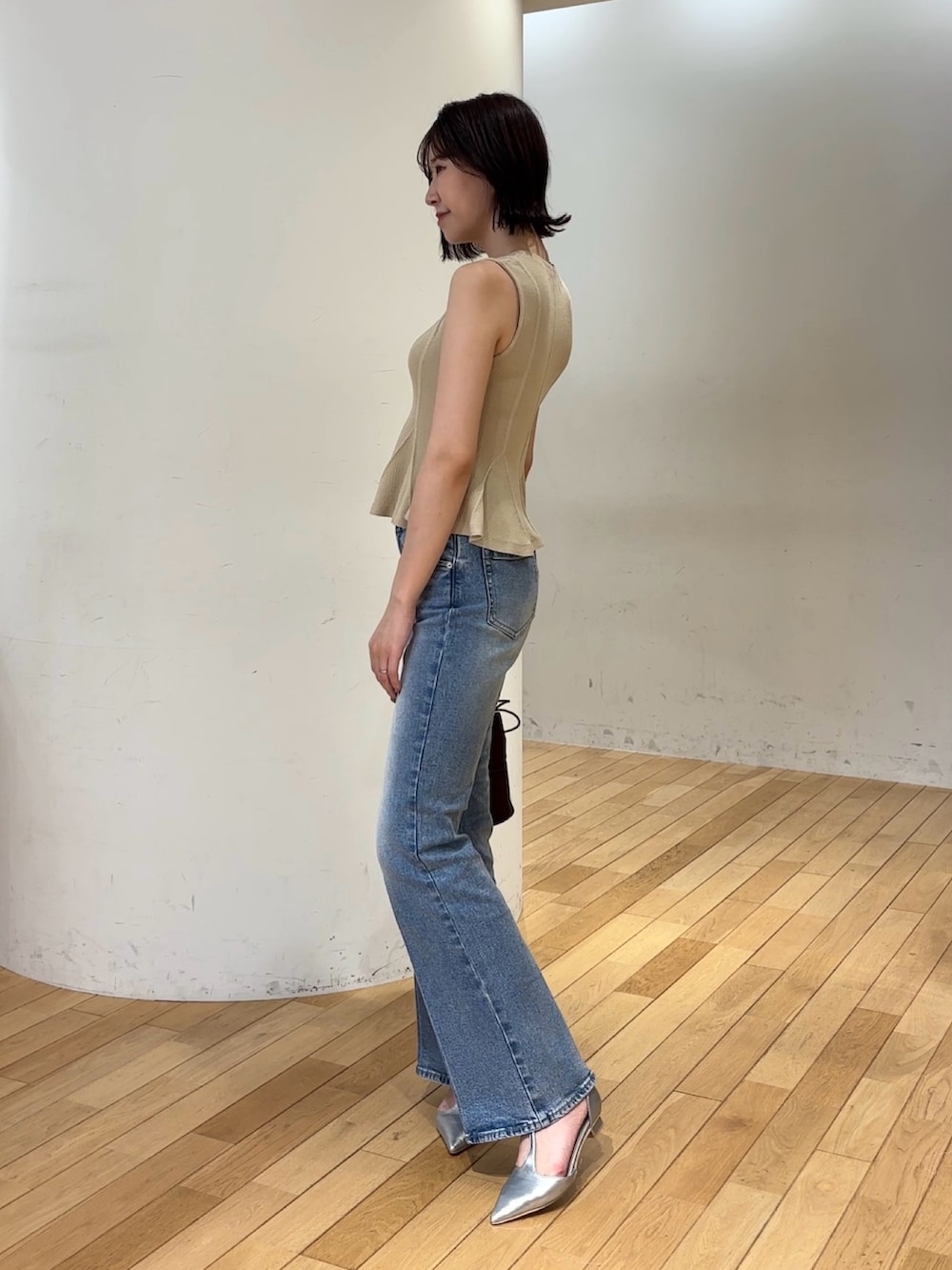 ブルー系のデニムパンツ、ブラウン系のハンドバッグ、シルバー系のパンプスを着用したレディースの夏コーディネートの4枚目の写真