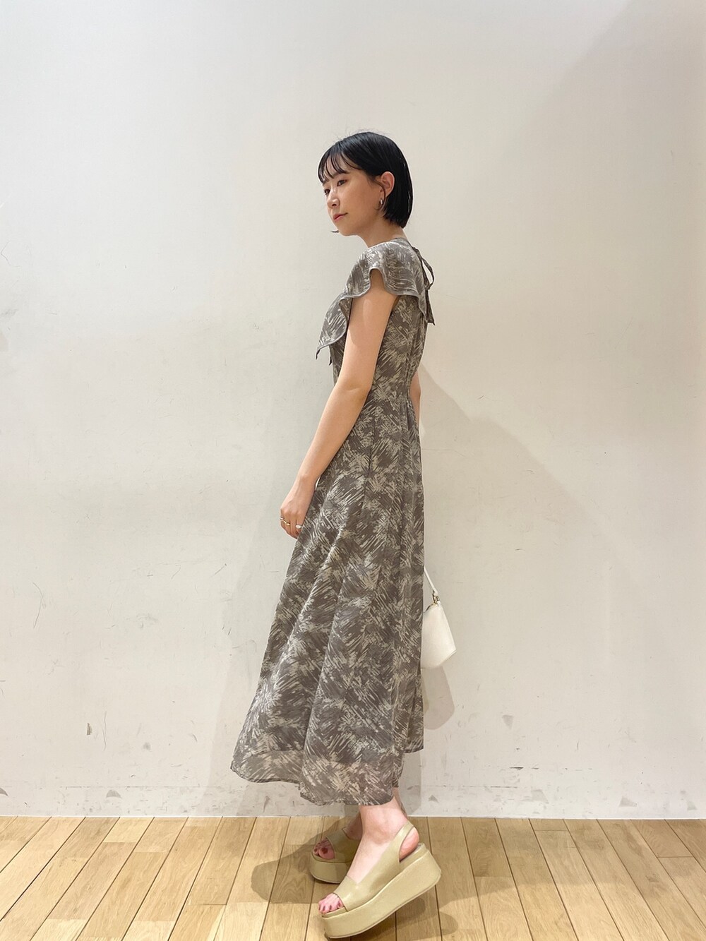 グレー系のワンピース、ホワイト系のハンドバッグ、ベージュ系のサンダルを着用したレディースの夏コーディネートの3枚目の写真