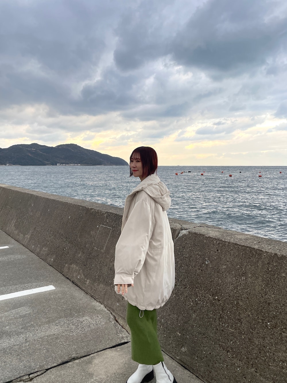 グリーン系のワンピース、ホワイト系のダウンジャケット/コートを着用したレディースの冬コーディネートの6枚目の写真