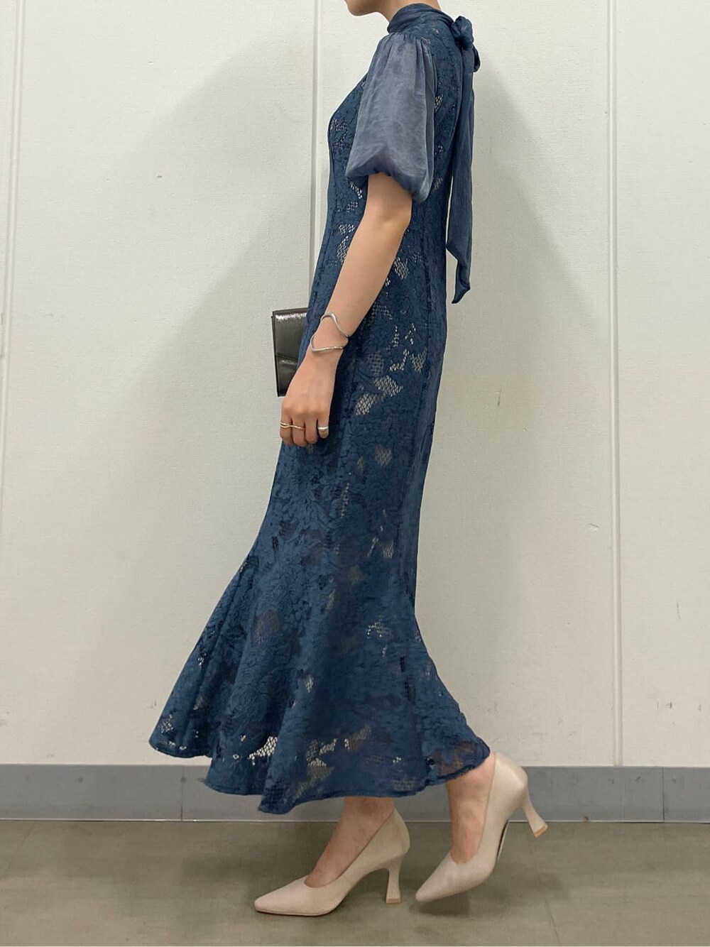 シルバー系のクラッチバッグ、ベージュ系のパンプス、ブルー系のドレスを着用したレディースの夏コーディネートの5枚目の写真