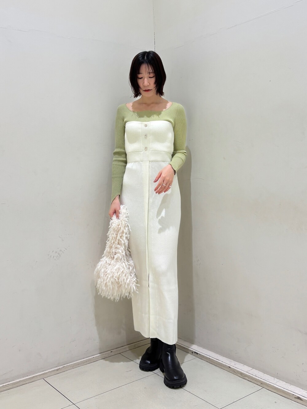 ホワイト系のワンピース、グリーン系のニット/セーター、ホワイト系のハンドバッグを着用したレディースの冬コーディネートの2枚目の写真