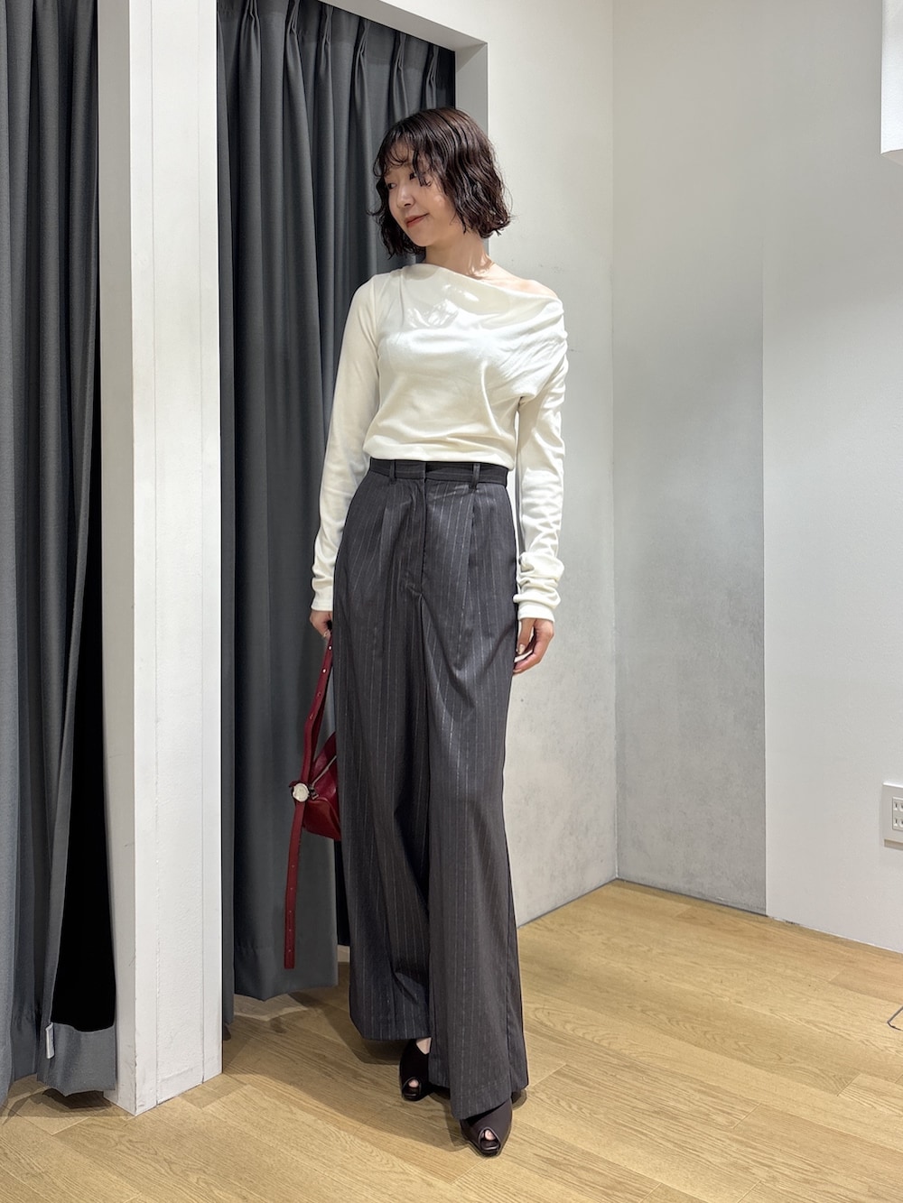 グレー系のその他パンツ、ホワイト系のニット/セーター、レッド系のハンドバッグを着用したレディースの秋コーディネートの7枚目の写真