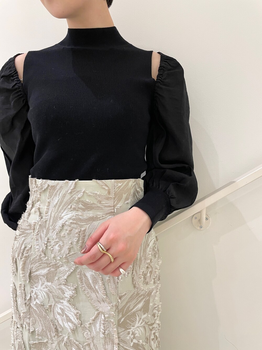 ブラック系のニット/セーター、ベージュ系のスカート、ホワイト系のハンドバッグを着用したレディースの冬コーディネートの6枚目の写真