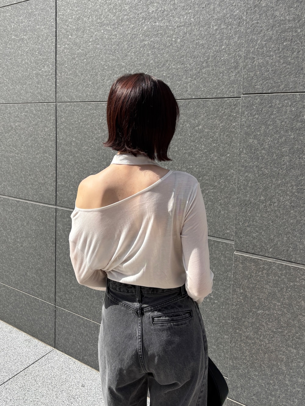 ブラック系のデニムパンツ、ホワイト系のTシャツ/カットソー、ブラック系のハンドバッグを着用したレディースの春コーディネートの5枚目の写真