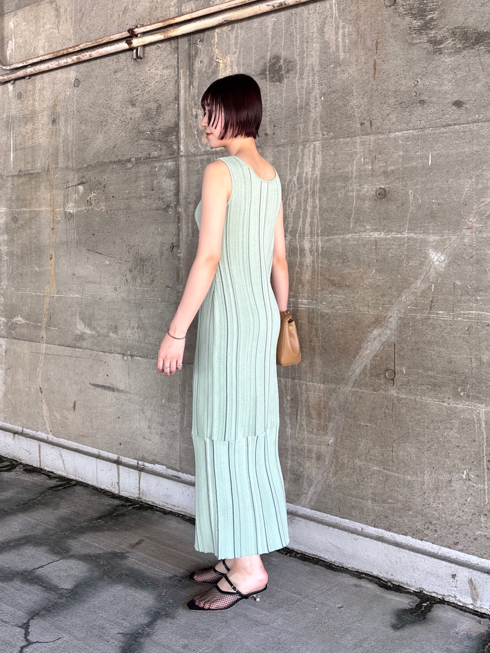 グリーン系のワンピース、ブラック系のサンダル、イエロー系のハンドバッグを着用したレディースの春コーディネートの3枚目の写真