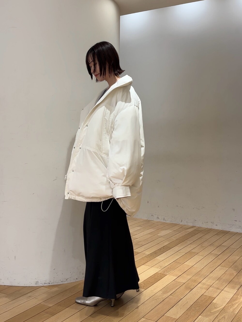 ブラック系のスカート、パープル系のニット/セーター、ホワイト系のダウンジャケット/コートを着用したレディースの冬コーディネートの3枚目の写真