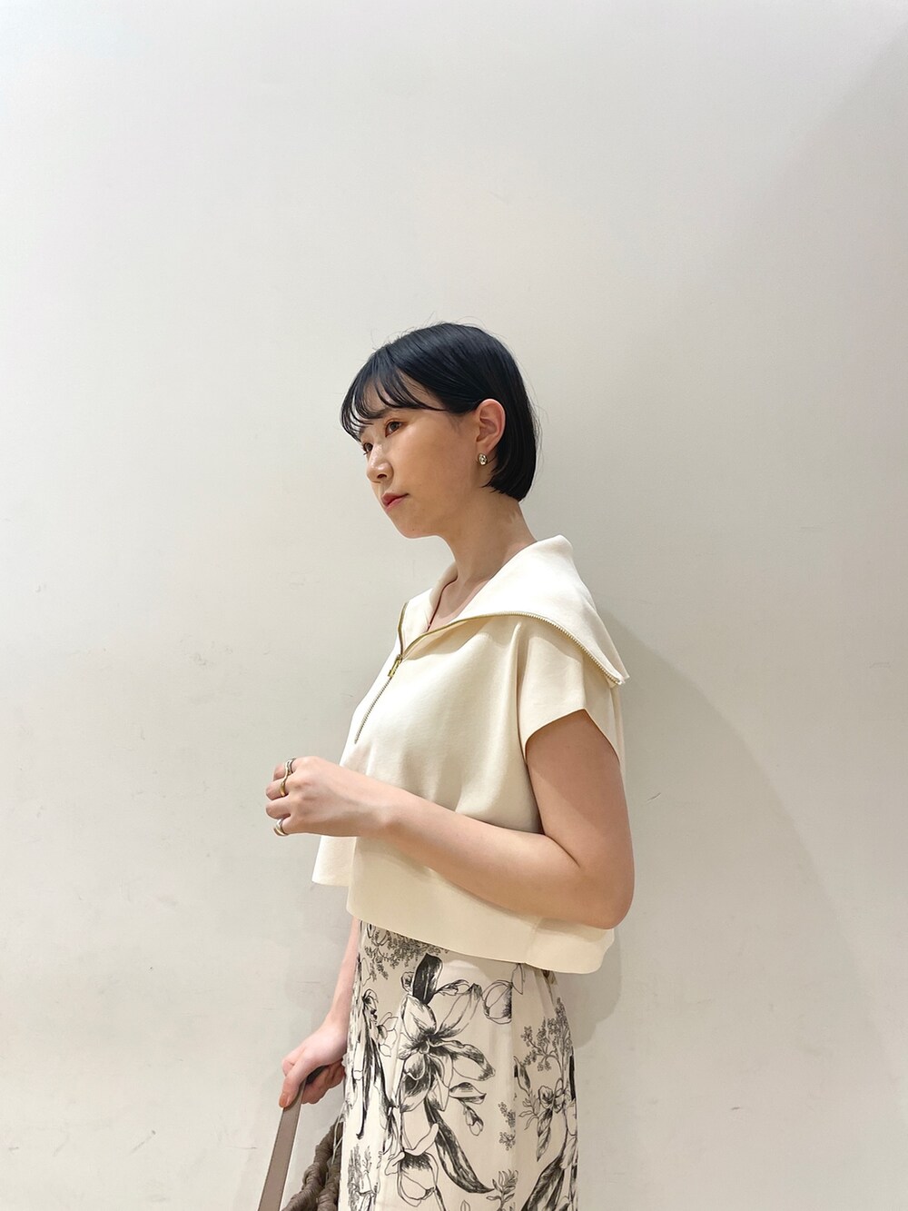 ホワイト系のニット/セーター、ホワイト系のスカート、ブラウン系のハンドバッグを着用したレディースの春コーディネートの6枚目の写真