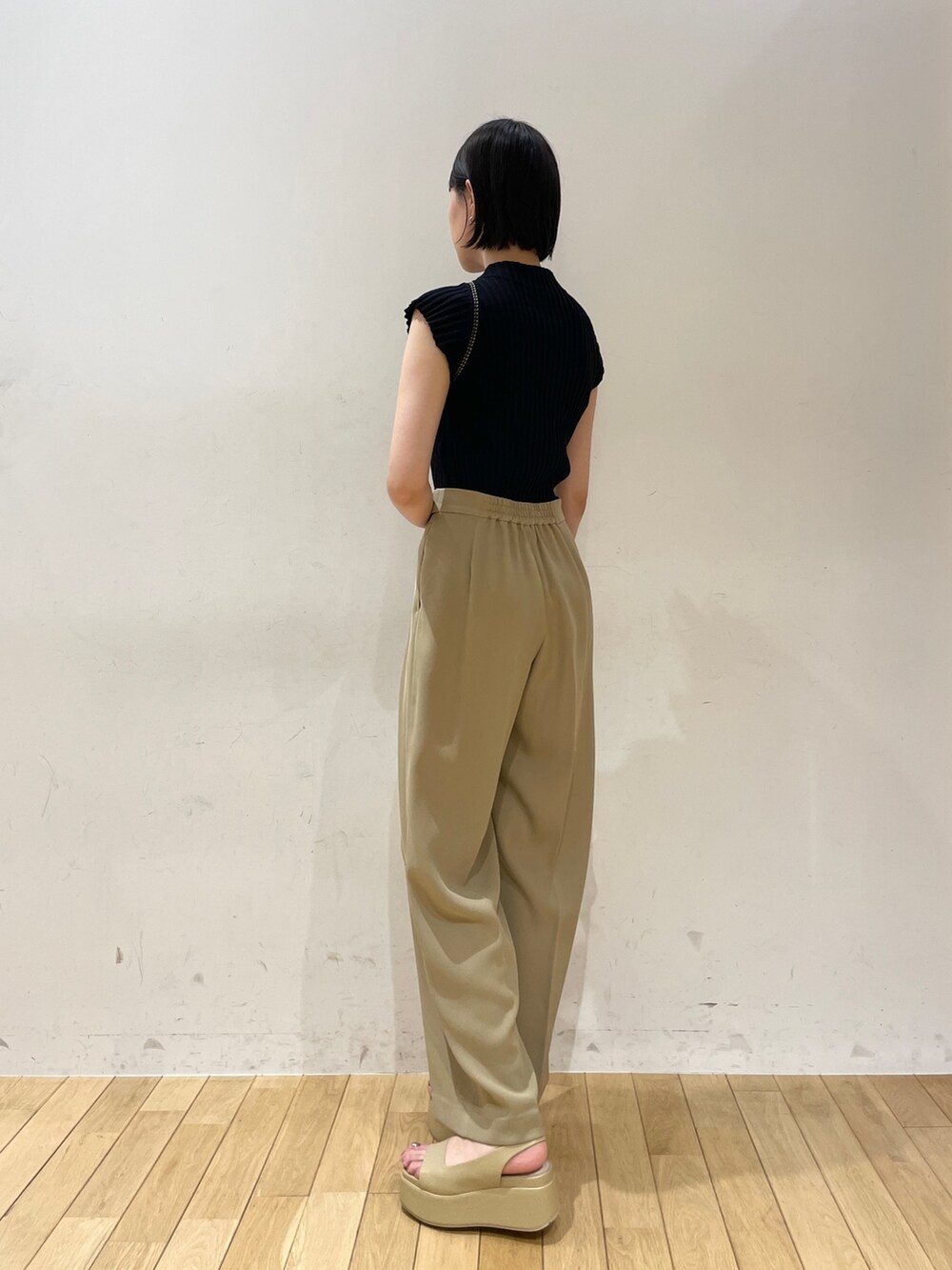 ブラック系のニット/セーター、ベージュ系のスラックス、ホワイト系のハンドバッグを着用したレディースの夏コーディネートの4枚目の写真