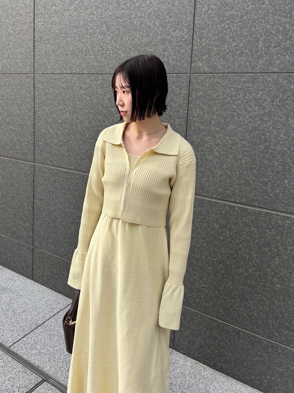 イエロー系のワンピース、ブラウン系のハンドバッグ、シルバー系のパンプスを着用したレディースの冬コーディネートの5枚目の写真