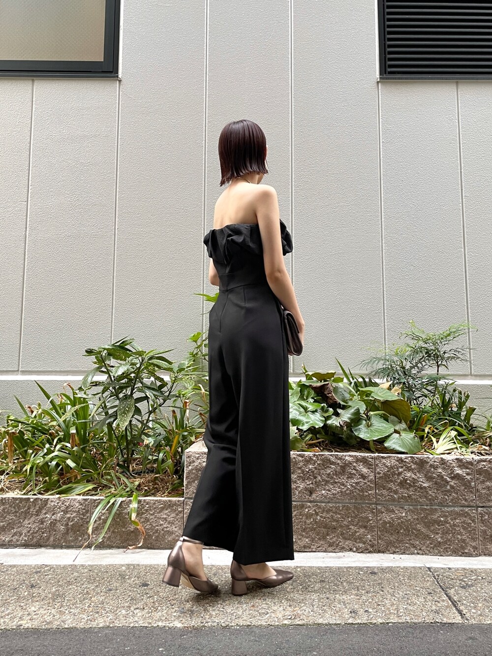 その他のパンプス、ブラック系のパンツドレス、シルバー系のハンドバッグを着用したレディースの秋コーディネートの8枚目の写真