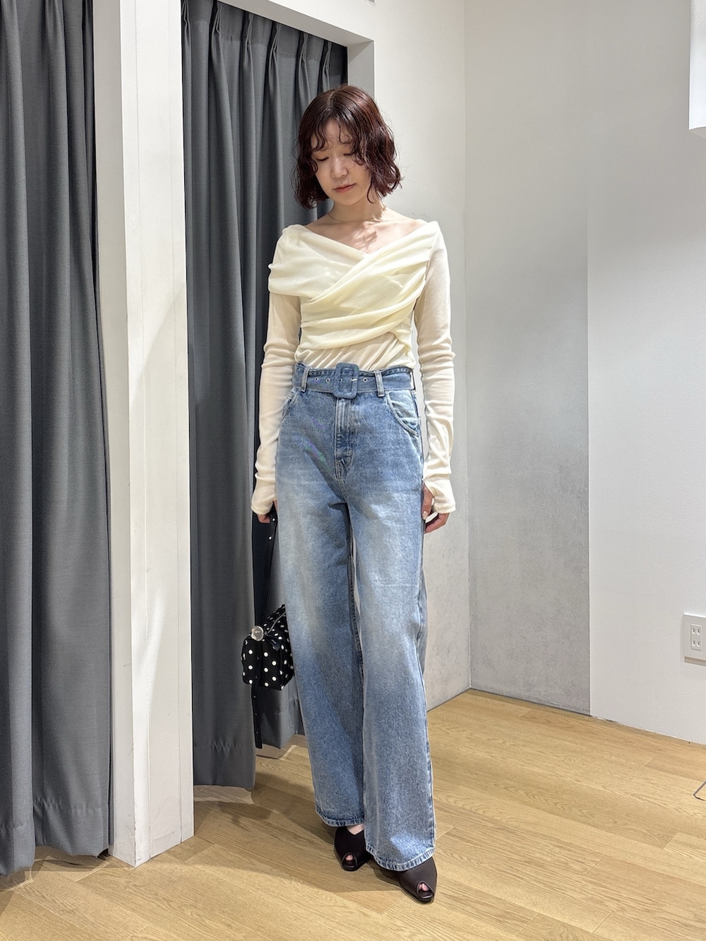 ホワイト系のTシャツ/カットソー、ブルー系のデニムパンツ、ブラック系のハンドバッグを着用したレディースの秋コーディネートの2枚目の写真