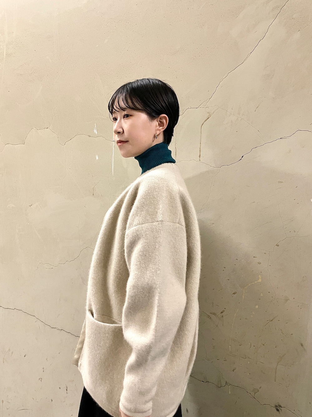 ブラック系のスカート、グリーン系のニット/セーター、ブラック系のブーツを着用したレディースの秋コーディネートの6枚目の写真