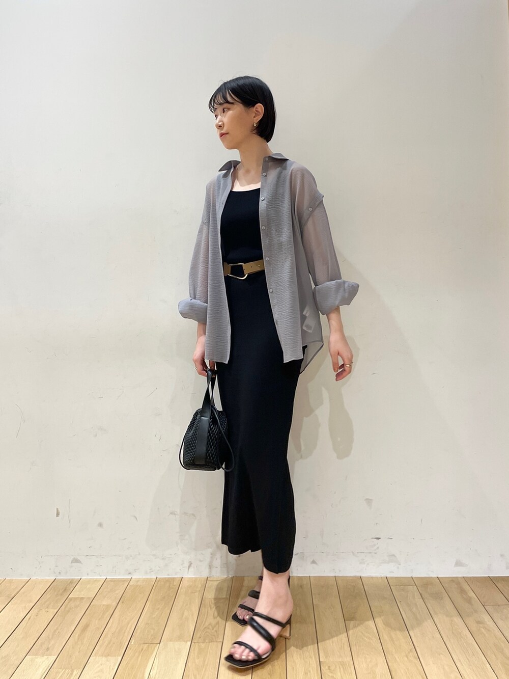 ブラック系のスカート、ブラウン系のハンドバッグ、ブラック系のサンダルを着用したレディースの春コーディネートの4枚目の写真