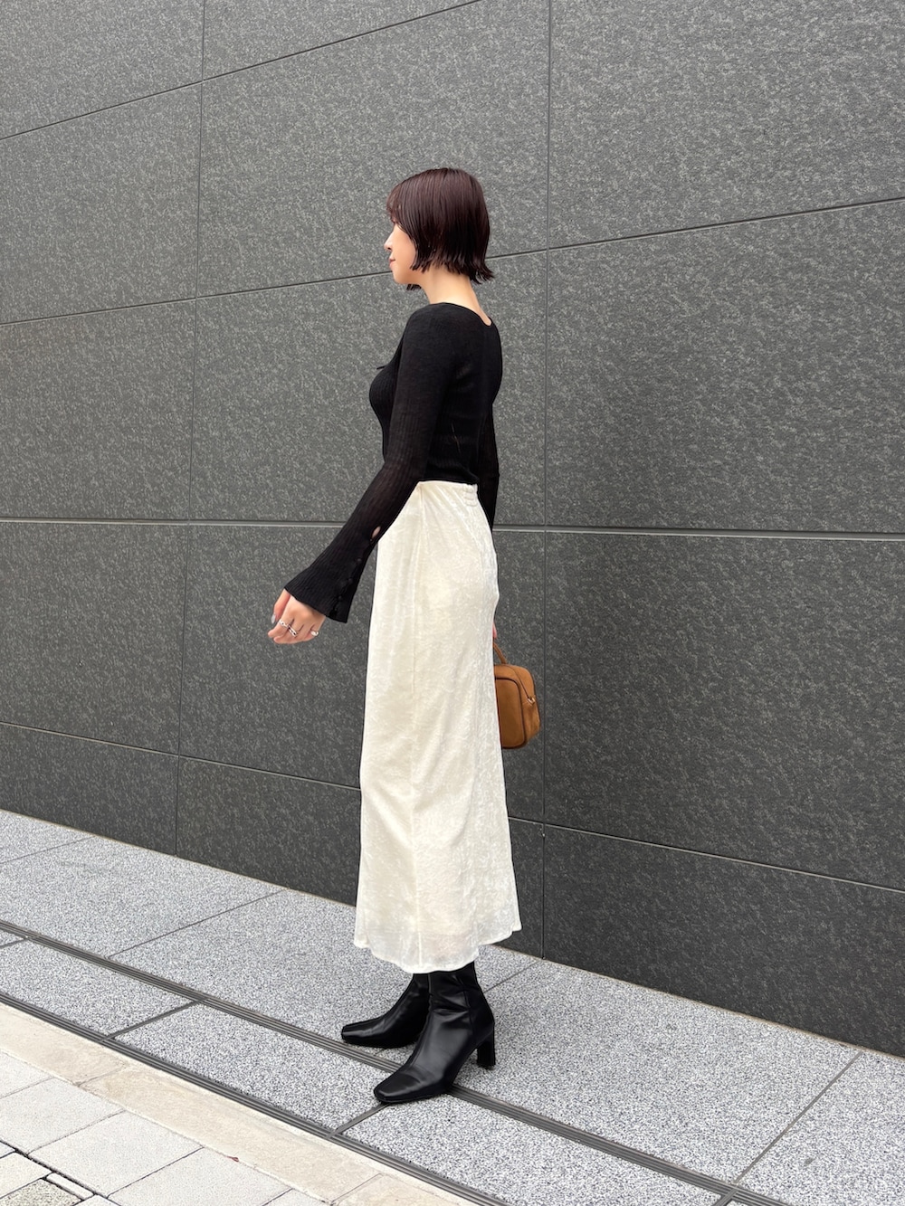 ホワイト系のスカート、ブラック系のニット/セーター、イエロー系のハンドバッグを着用したレディースの秋コーディネートの3枚目の写真