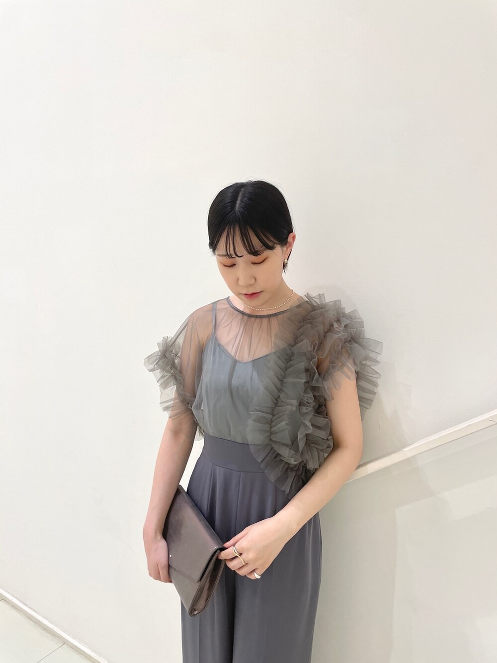 グレー系のパンツドレス、シルバー系のハンドバッグ、シルバー系のパンプスを着用したレディースの春コーディネートの5枚目の写真