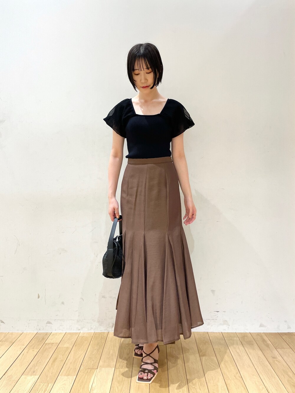 ブラウン系のスカート、ブラウン系のサンダル、ブラック系のハンドバッグを着用したレディースの夏コーディネートの2枚目の写真