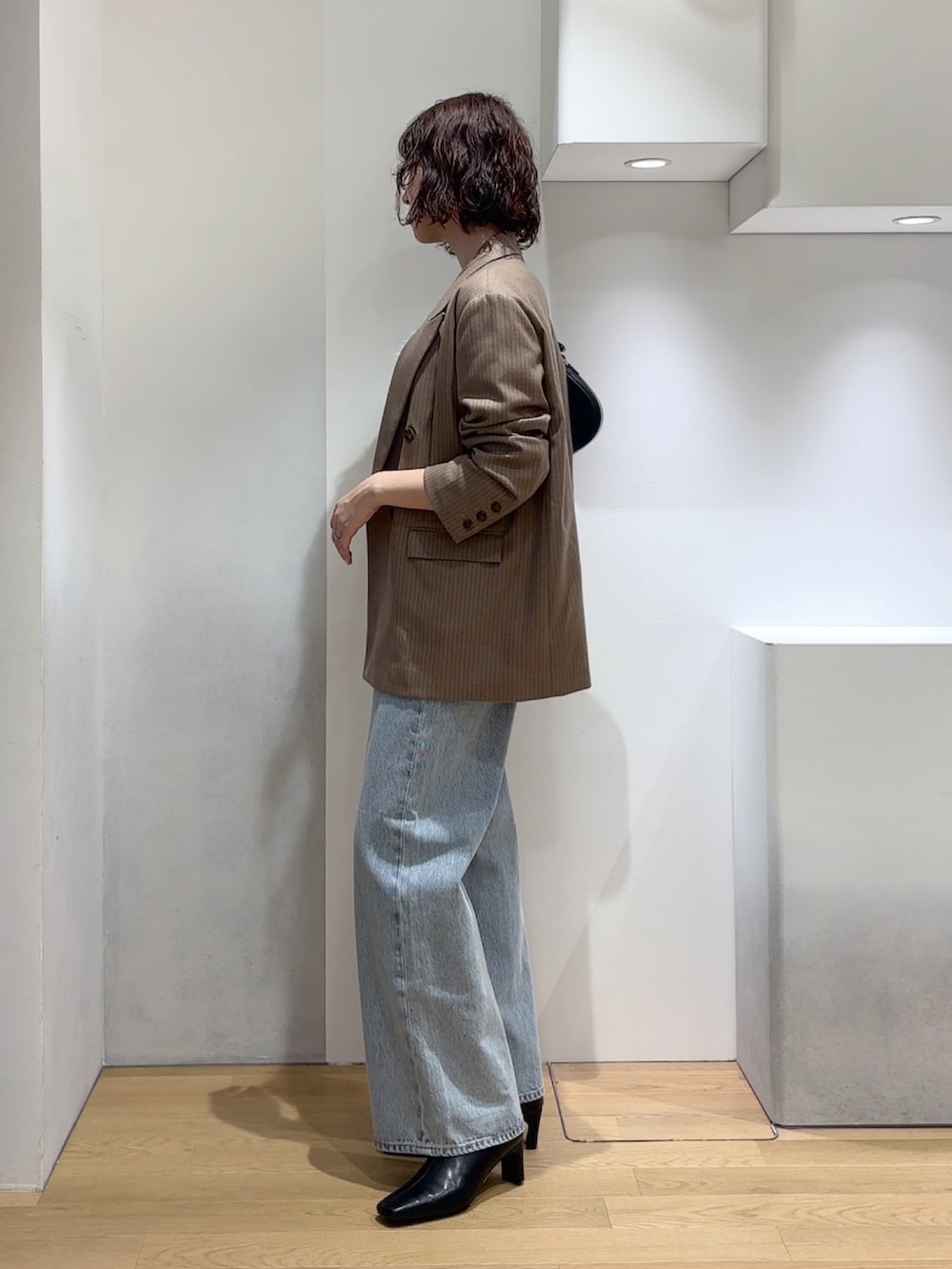 ホワイト系のニット/セーター、ブルー系のデニムパンツ、ブラック系のブーツを着用したレディースの秋コーディネートの2枚目の写真