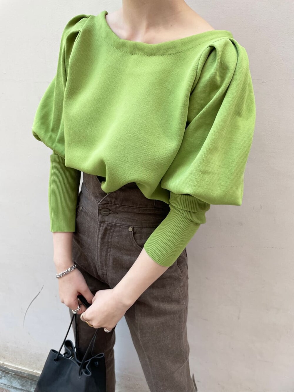 ブラック系のその他シューズ、ブラック系のハンドバッグ、グリーン系のニット/セーターを着用したレディースの冬コーディネートの7枚目の写真