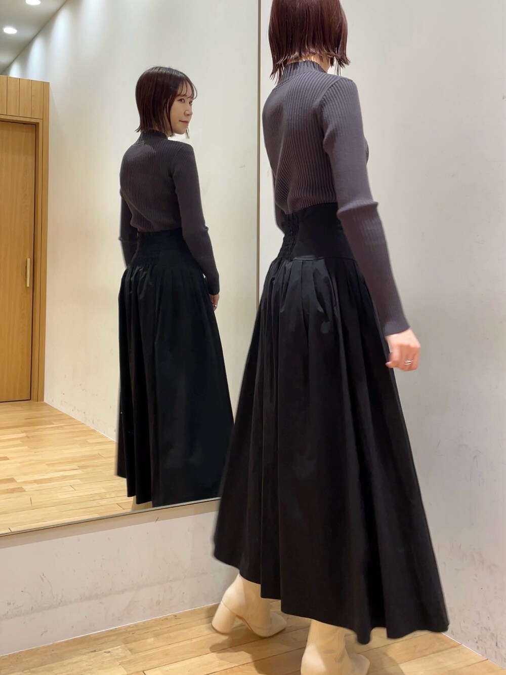 ホワイト系のブーツ、ブラック系のスカート、グレー系のニット/セーターを着用したレディースの冬コーディネートの2枚目の写真