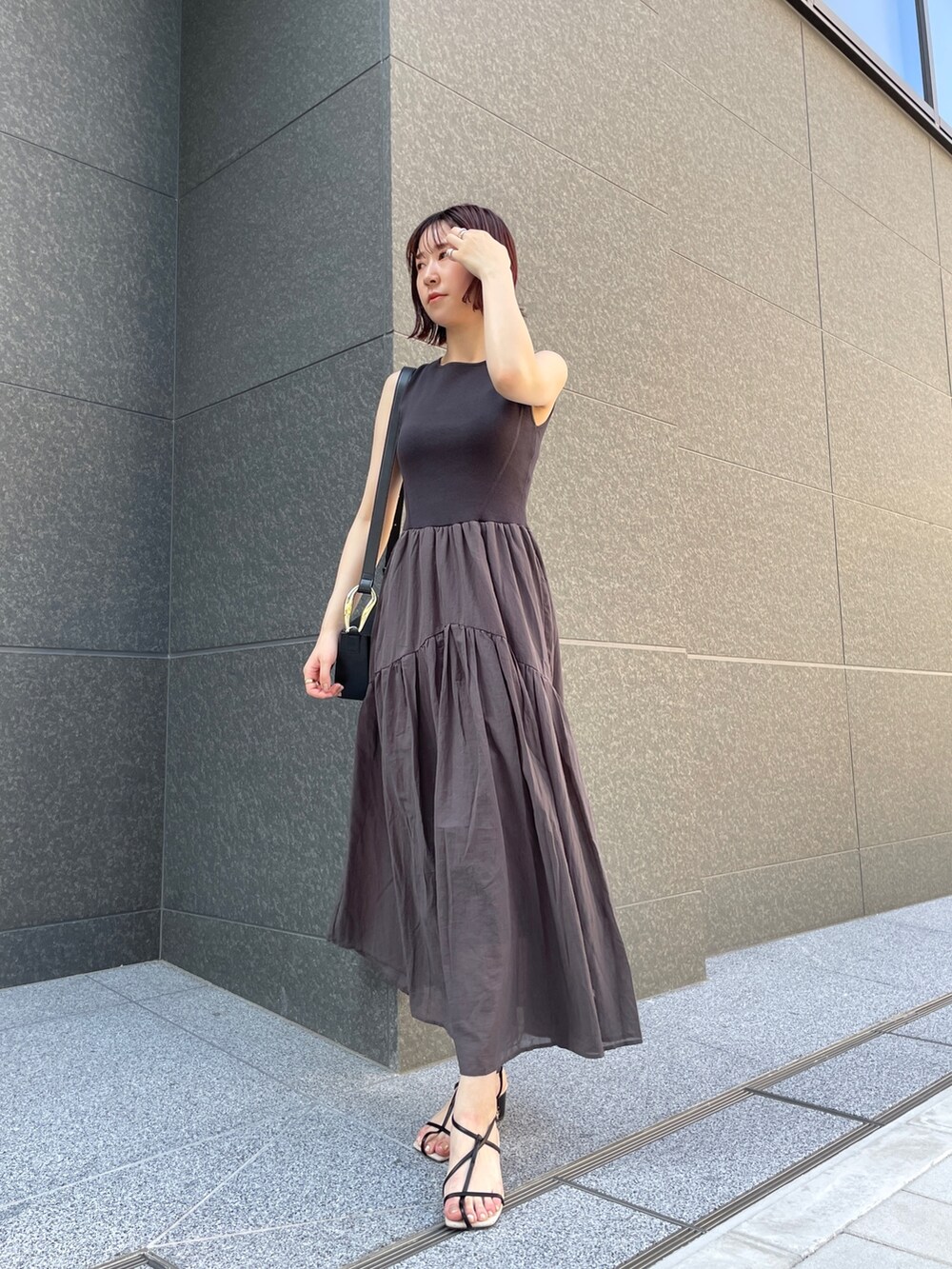 ブラック系のサンダル、グレー系のワンピース、ブラック系のショルダーバッグを着用したレディースの夏コーディネートの2枚目の写真