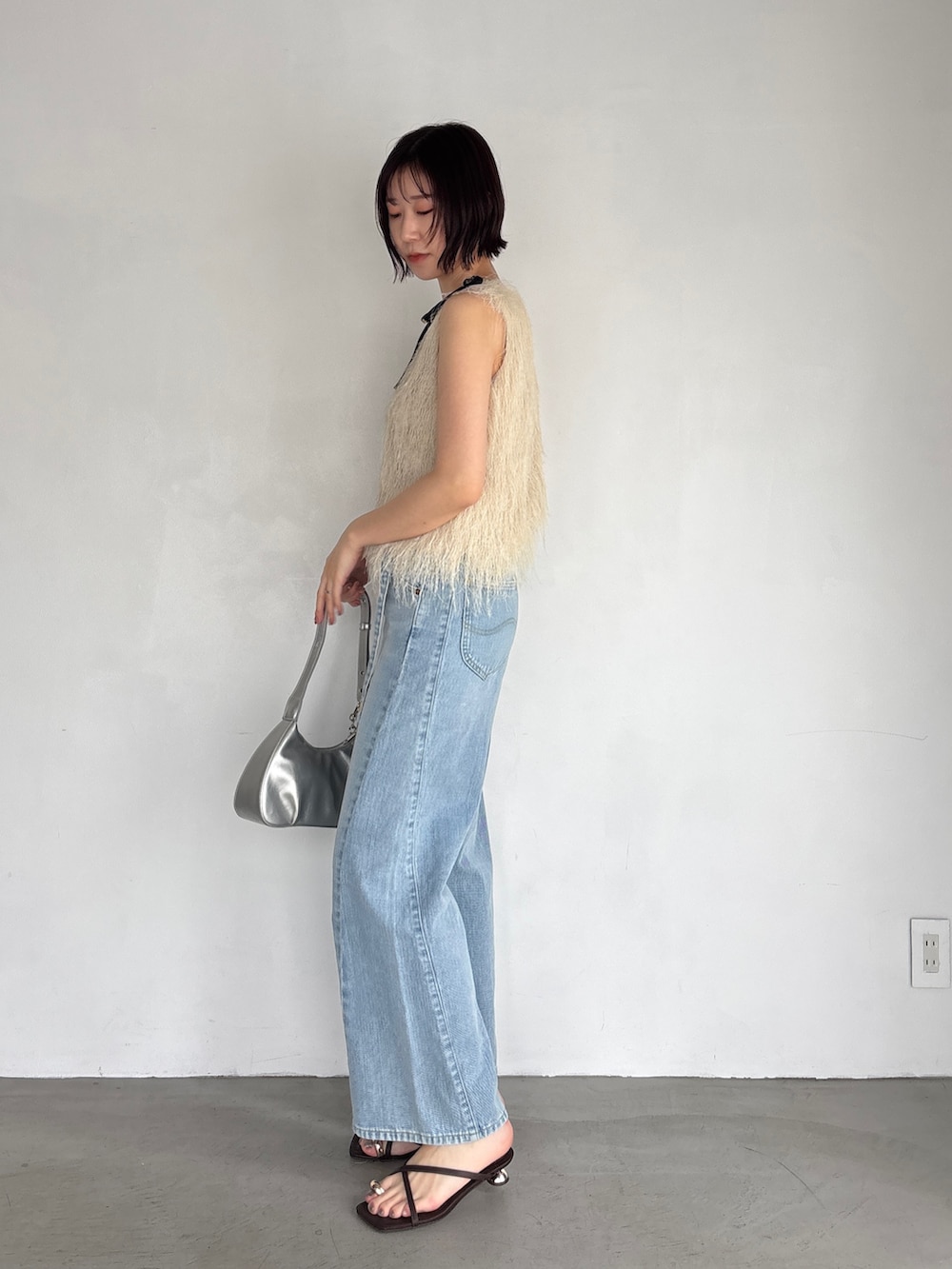 ホワイト系のTシャツ/カットソー、ブルー系のデニムパンツ、シルバー系のハンドバッグを着用したレディースの春コーディネートの3枚目の写真