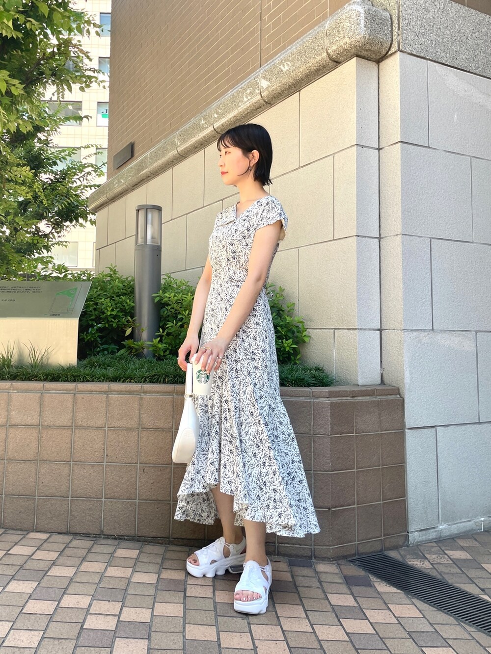 ホワイト系のワンピース、ホワイト系のハンドバッグを着用したレディースの夏コーディネートの2枚目の写真