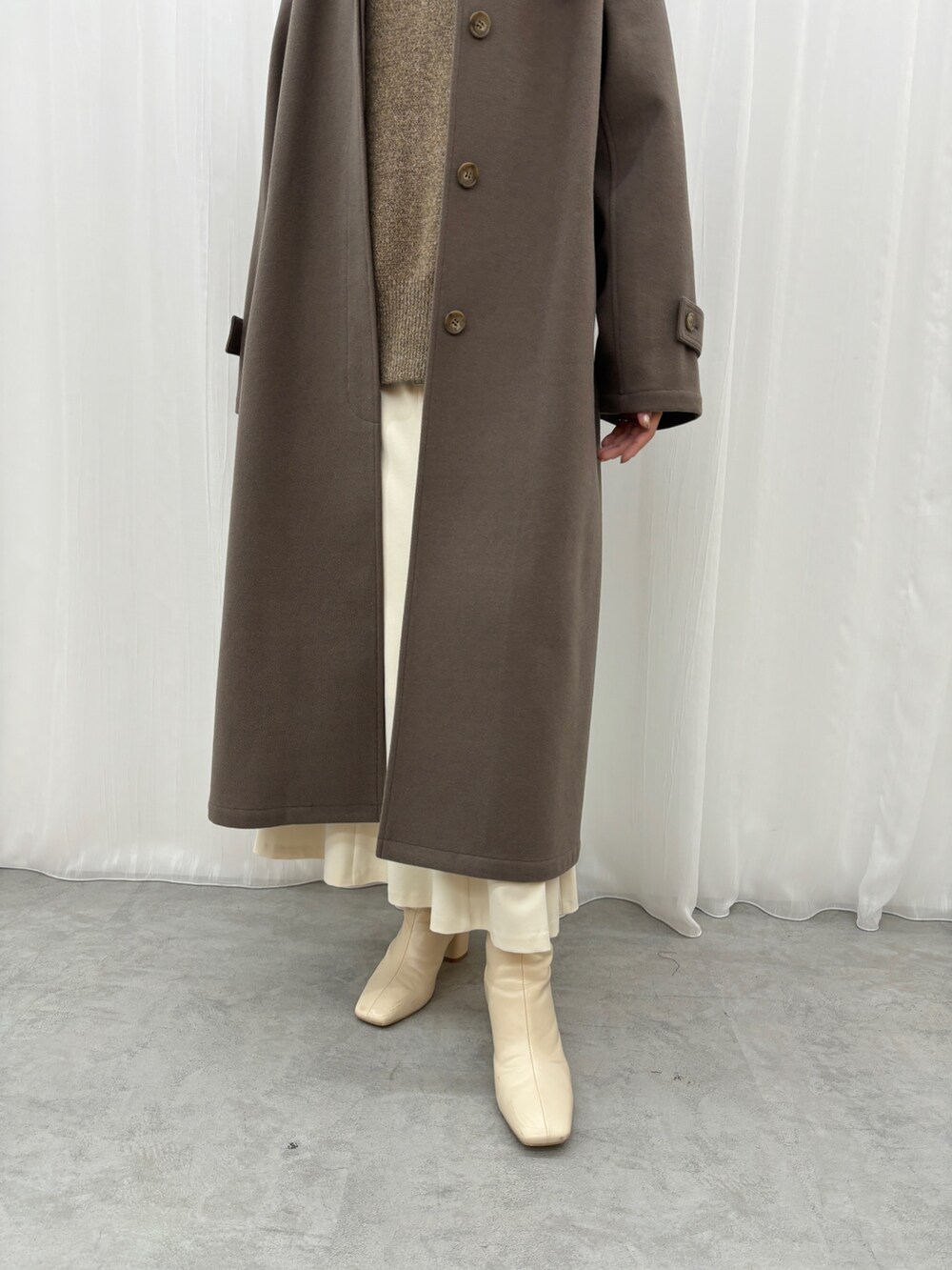 ホワイト系のスカート、ブラウン系のニット/セーター、ブラウン系のステンカラーコートを着用したレディースの秋コーディネートの6枚目の写真