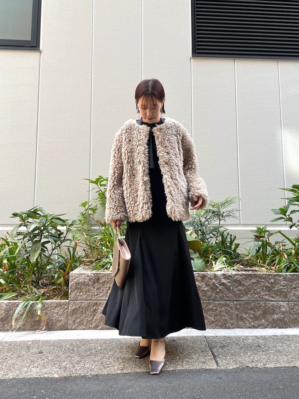 ゴールド系のハンドバッグ、その他のパンプス、ブラック系のドレスを着用したレディースの秋コーディネートの3枚目の写真