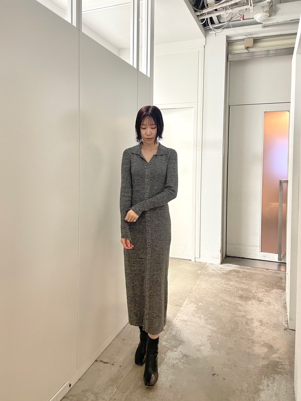 ブラック系のブーツ、グレー系のワンピースを着用したレディースの春コーディネートの2枚目の写真