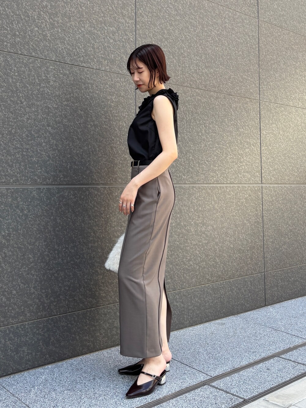 グレー系のスカート、ホワイト系のボストンバッグ、ブラウン系のパンプスを着用したレディースの夏コーディネートの3枚目の写真