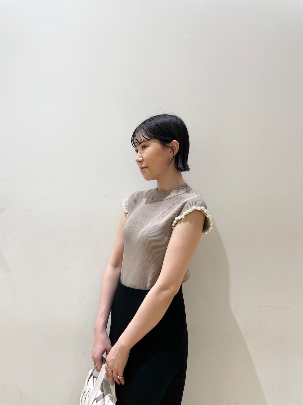 ブラック系のスカート、ベージュ系のニット/セーター、ホワイト系のショルダーバッグを着用したレディースの夏コーディネートの6枚目の写真