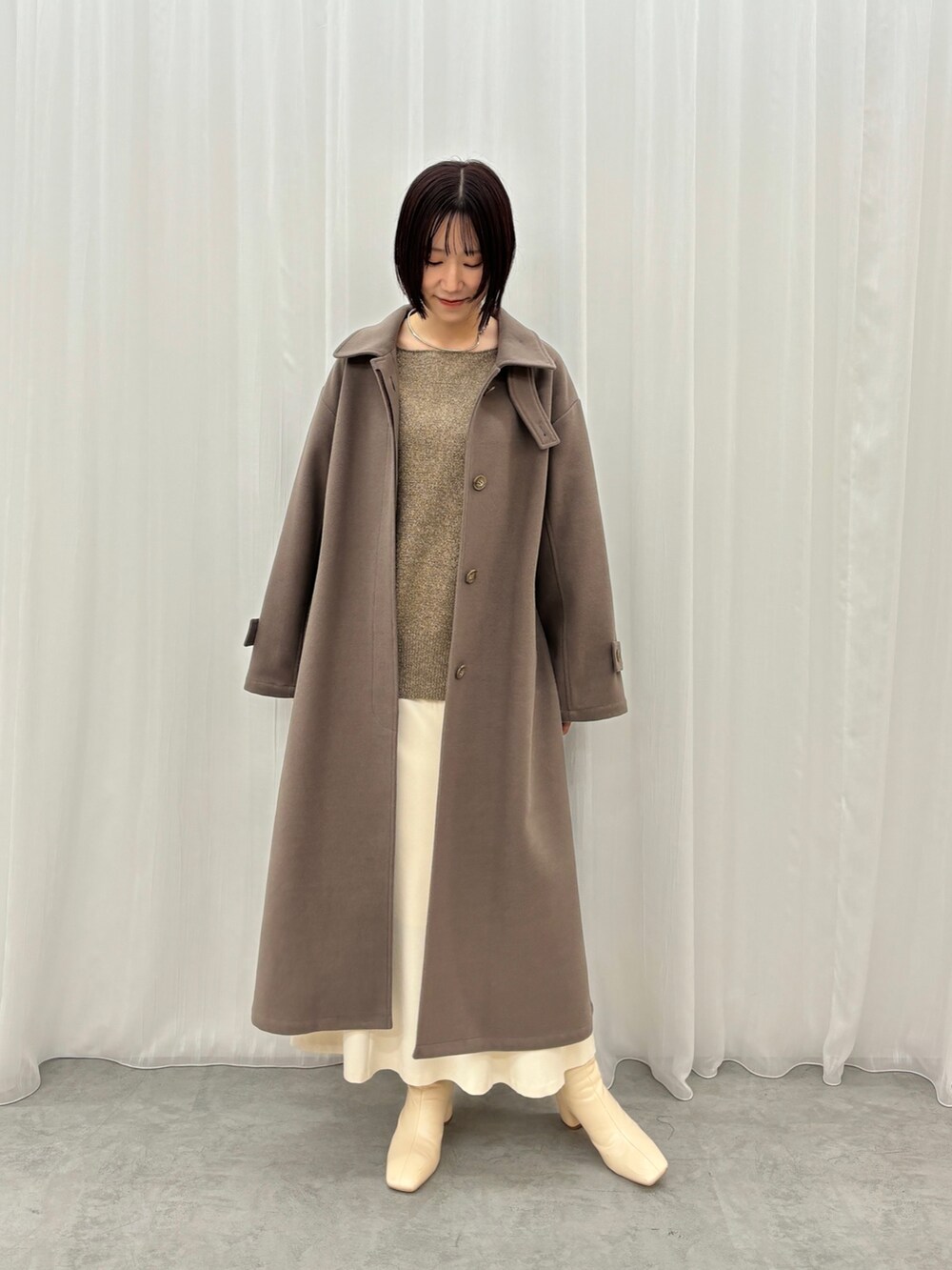 ホワイト系のスカート、ブラウン系のニット/セーター、ブラウン系のステンカラーコートを着用したレディースの秋コーディネートの2枚目の写真