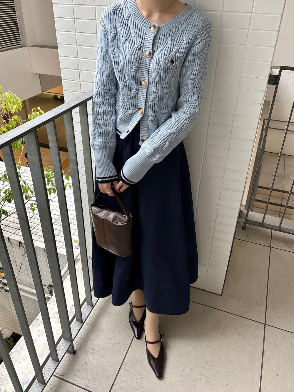 ブルー系のスカート、ブルー系のワンピース、ブラウン系のハンドバッグを着用したレディースの春コーディネートの3枚目の写真