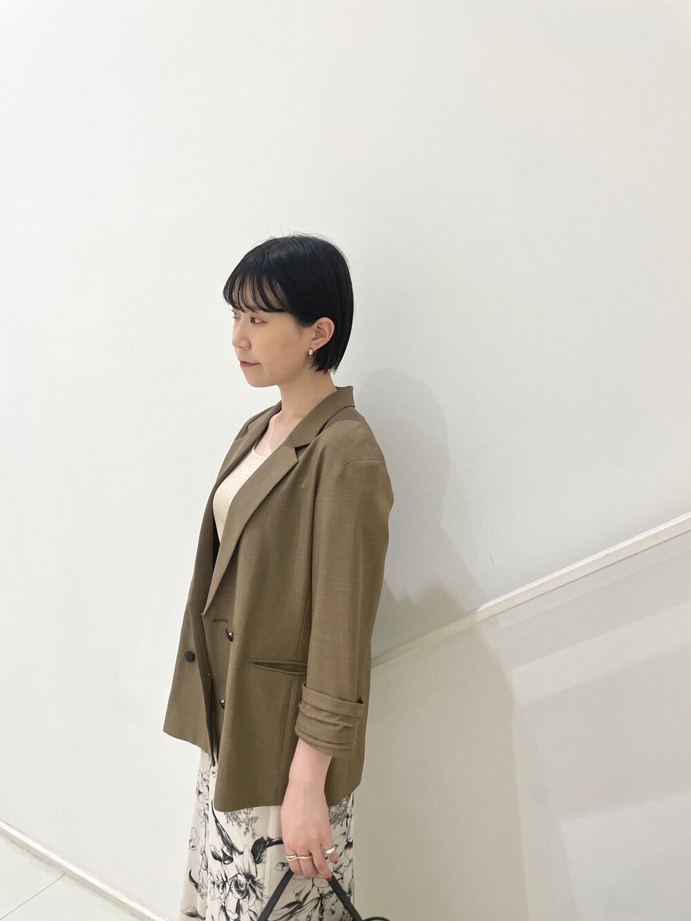 ブラウン系のテーラードジャケット、ベージュ系のニット/セーター、ホワイト系のスカートを着用したレディースの春コーディネートの6枚目の写真