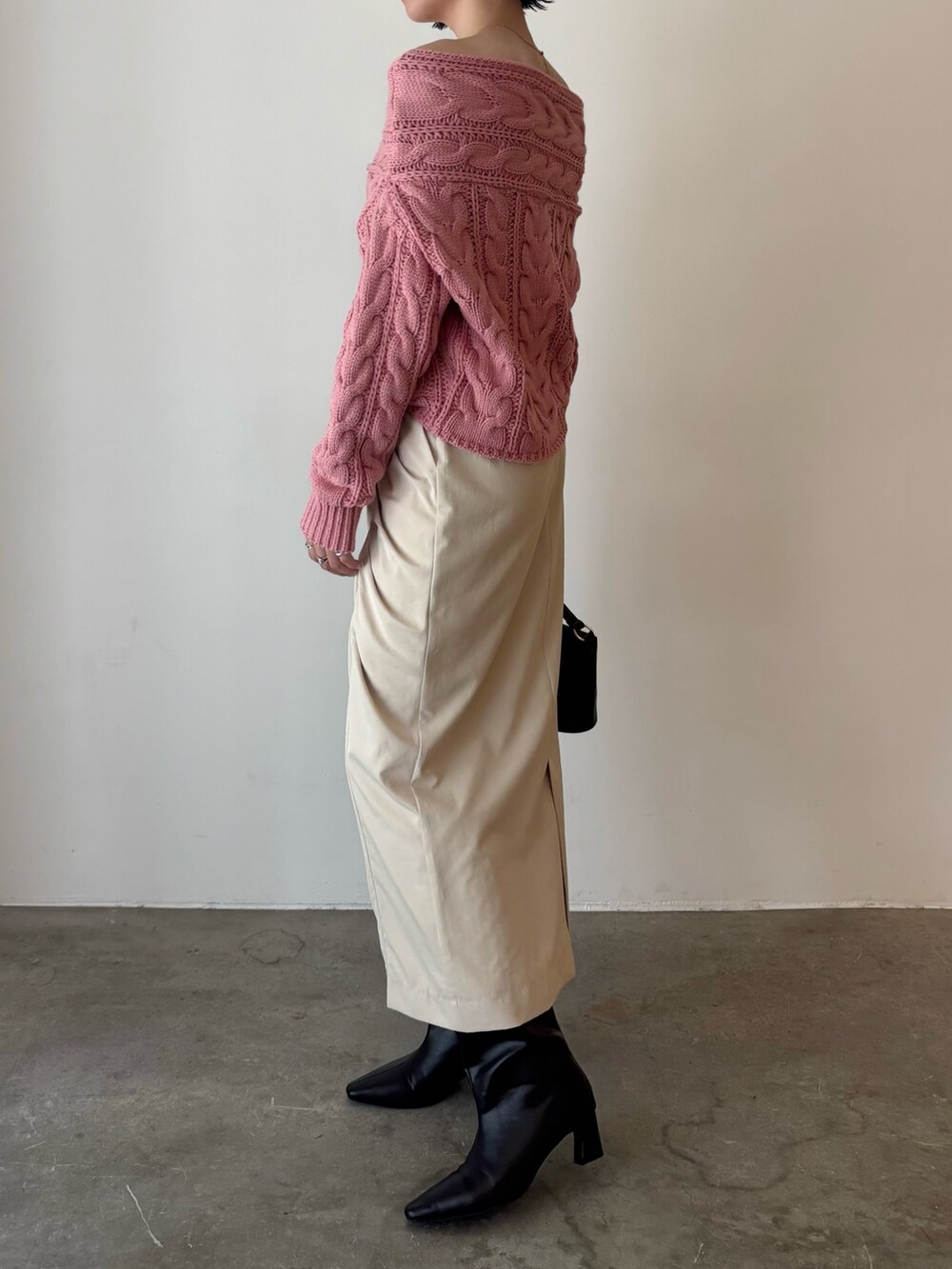 ピンク系のニット/セーター、ベージュ系のスカート、ブラウン系のハンドバッグを着用したレディースの秋コーディネートの3枚目の写真