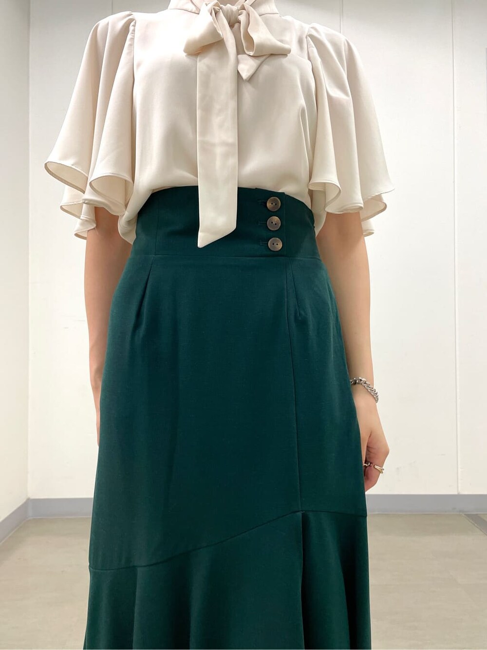 ホワイト系のシャツ/ブラウス、グリーン系のスカート、ブラック系のブーツを着用したレディースの秋コーディネートの6枚目の写真